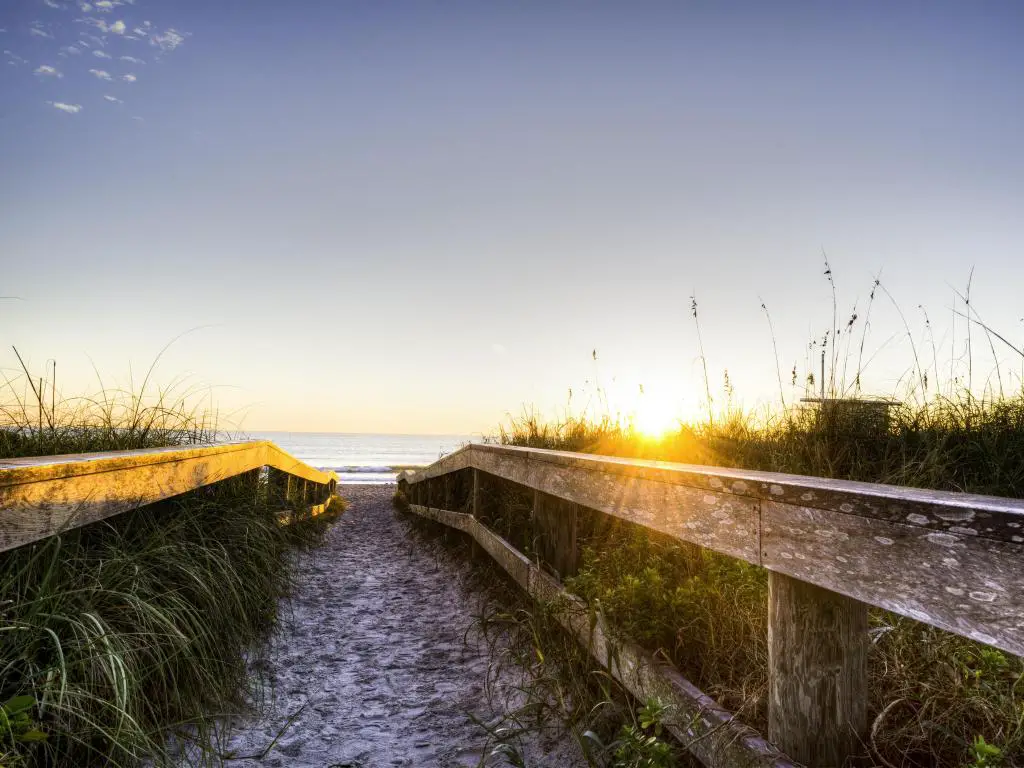 Cocoa Beach, Florida, EE.UU. tomada al amanecer con cercas de madera que conducen hacia el mar en la distancia.