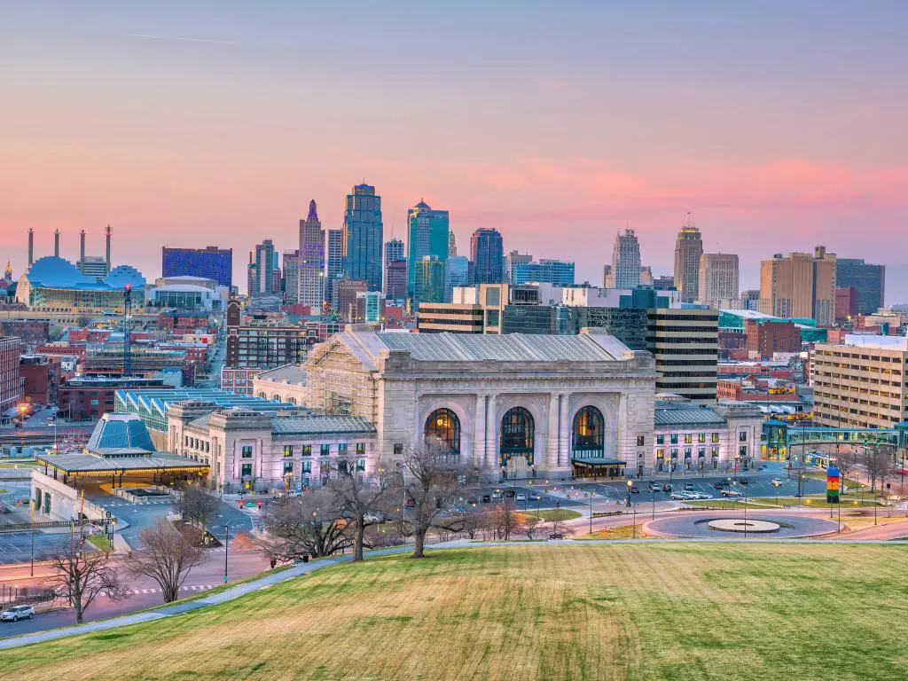 Kansas City, Missouri, Estados Unidos, el centro de la ciudad con Union Station tomada al atardecer con un borde de hierba en primer plano.