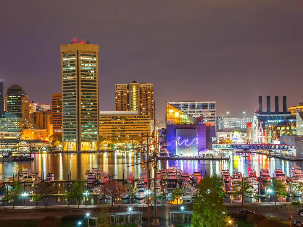Baltimore, Maryland, EE.UU. con vistas al centro de Baltimore por la noche, con barcos en el puerto en primer plano.