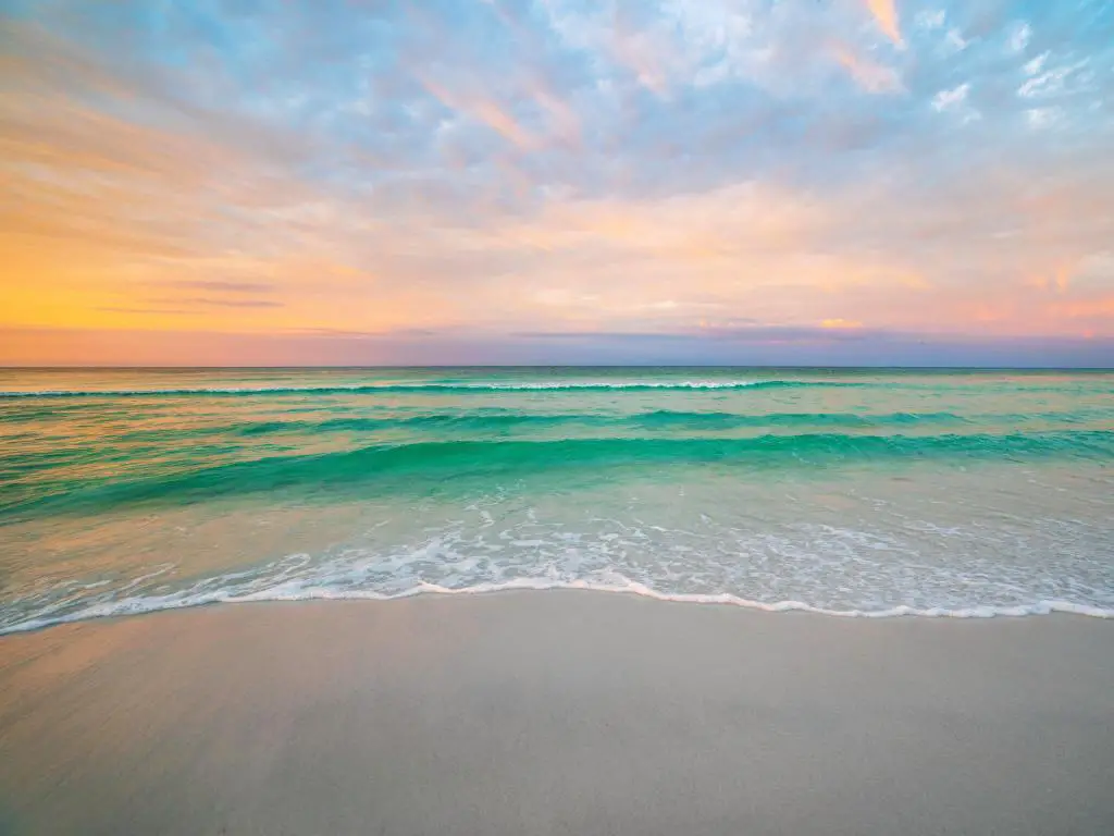 Destin, Florida, EE.UU. durante el amanecer de la mañana con aguas tranquilas y arena suave en primer plano.