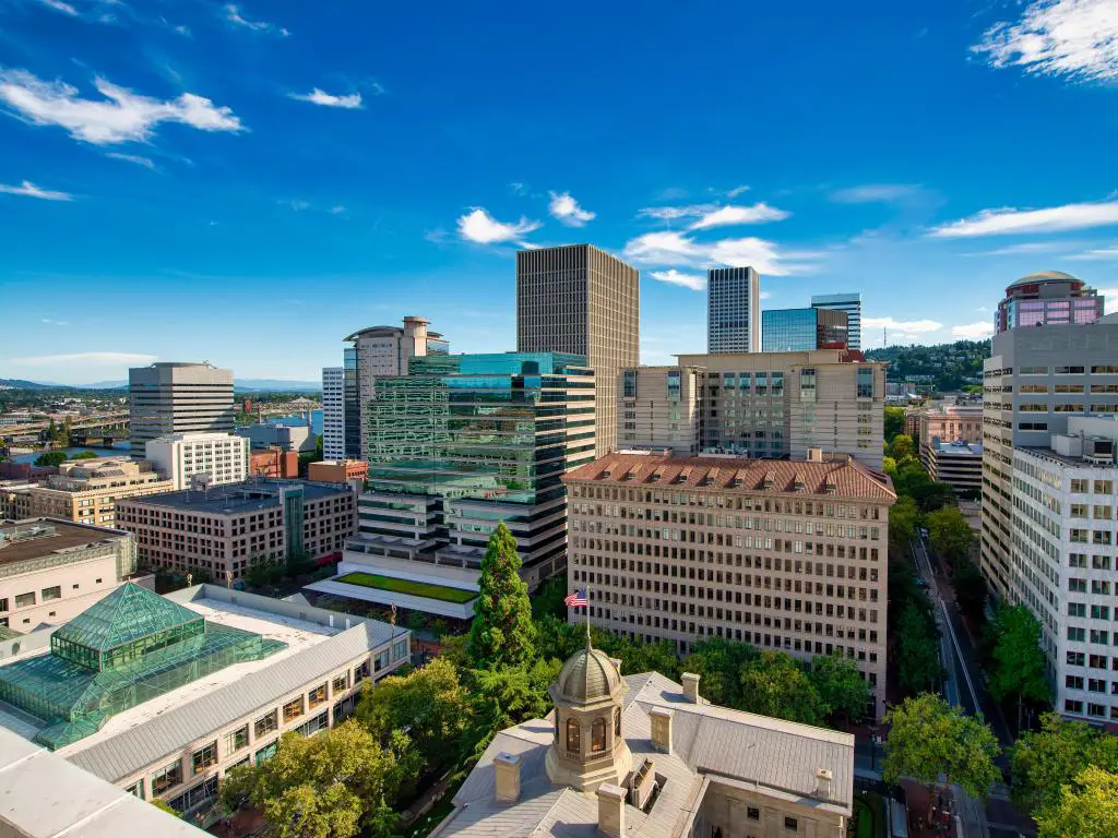 Portland, Oregón, EE.UU. con edificios y rascacielos tomados como una vista aérea contra un cielo azul.