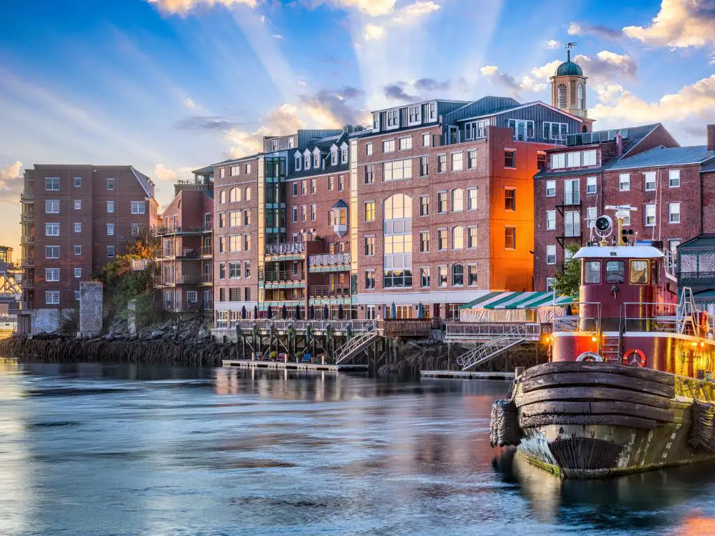 Portsmouth, New Hampshire, EE.UU. tomada con el paisaje urbano de la ciudad en el fondo, un barco de pesca en primer plano en el río y un fondo soleado.