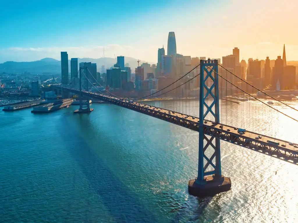 San Francisco, CA, EE.UU. con una vista aérea del Puente de la Bahía tomada al atardecer con el horizonte de la ciudad al fondo. 