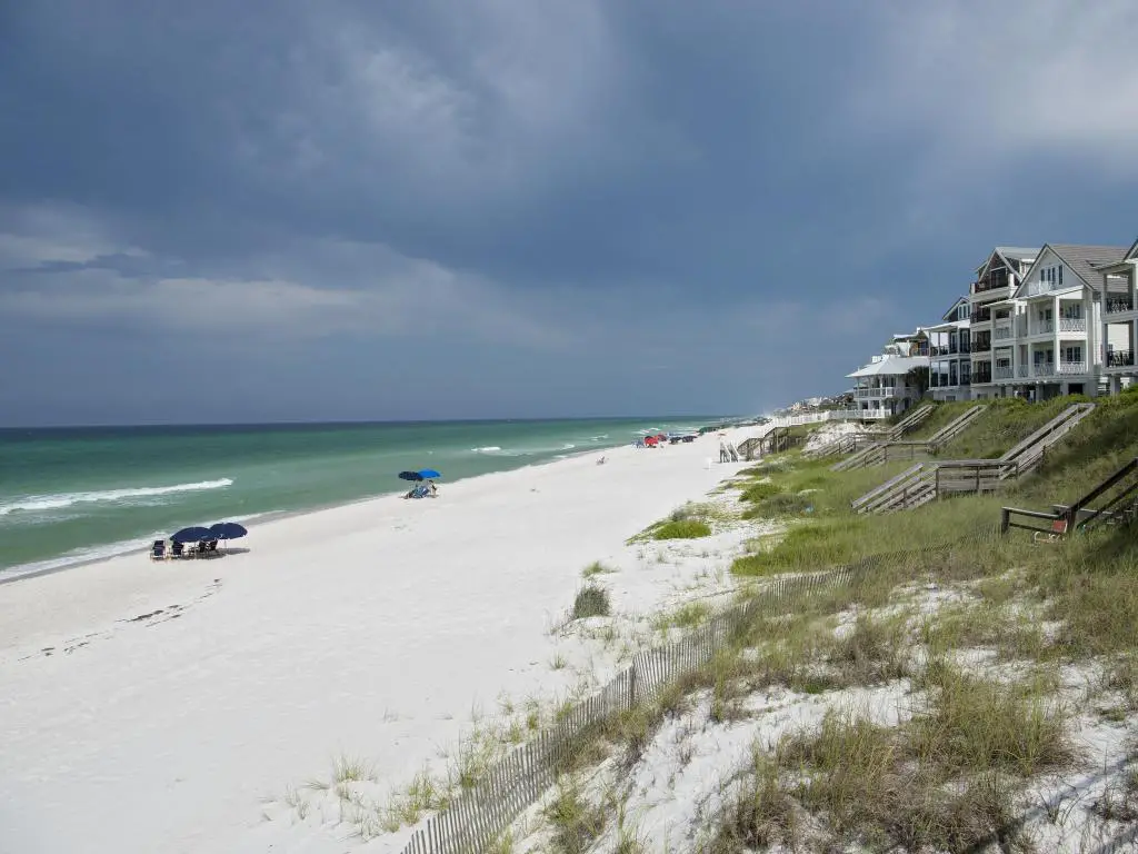 Rosemary Beach, Florida, EE.UU. con casas de playa y escalones que conducen a las dunas de arena, playa de arena blanca y mar con nubes oscuras arriba.