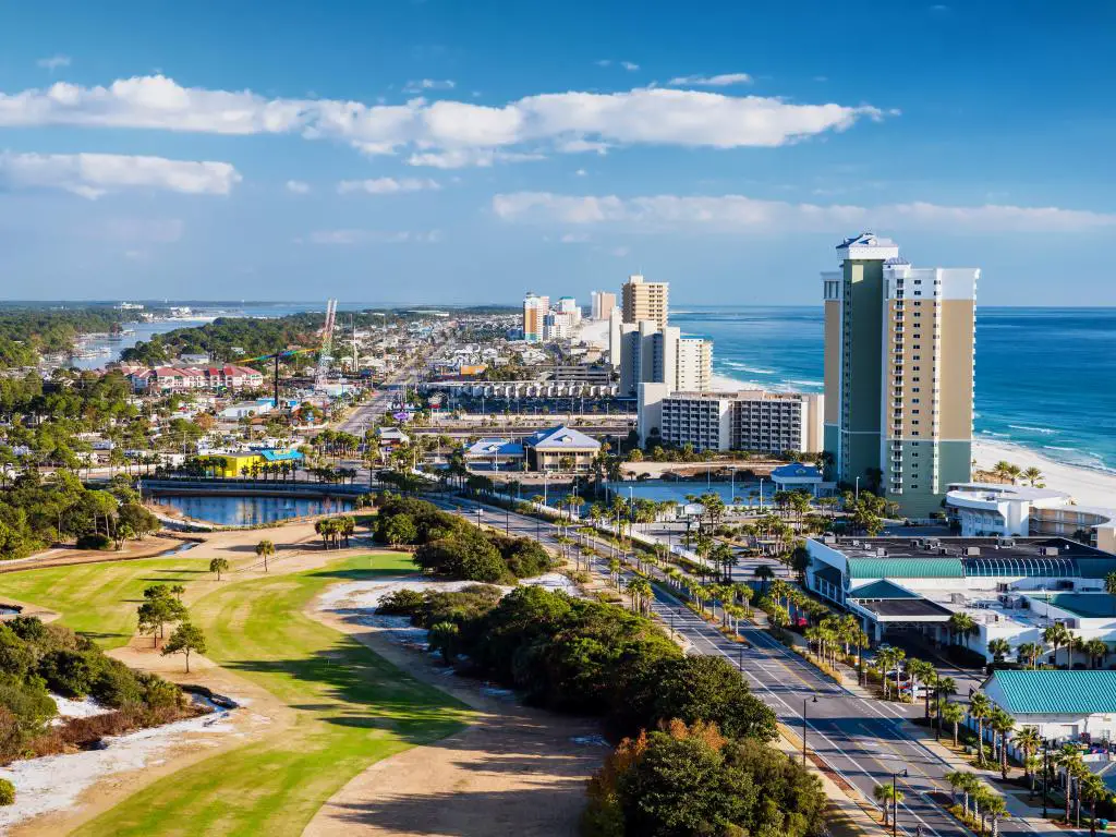 Panama City Beach, Florida, EE.UU., vista de Front Beach Road con vegetación detrás, rascacielos frente a la playa y el mar y tomada en un día soleado.