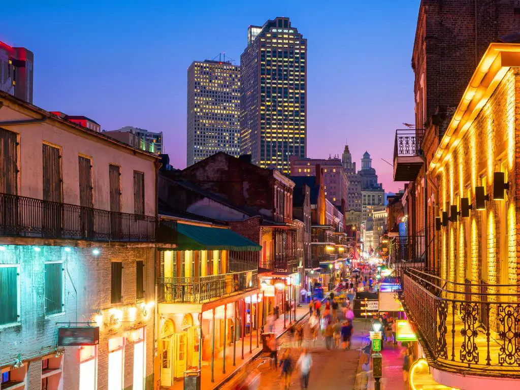 Barrio Francés, Nueva Orleans, EE.UU. con los pubs y bares con luces de neón tomadas por la noche y rascacielos en la distancia.