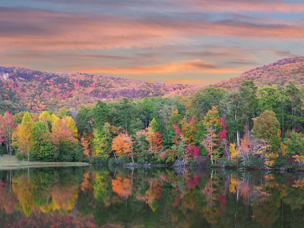 Cheaha State Park, Alabama, EE.UU. con un panorama del hermoso follaje de otoño reflejado en el lago, árboles y colinas a lo lejos al atardecer.