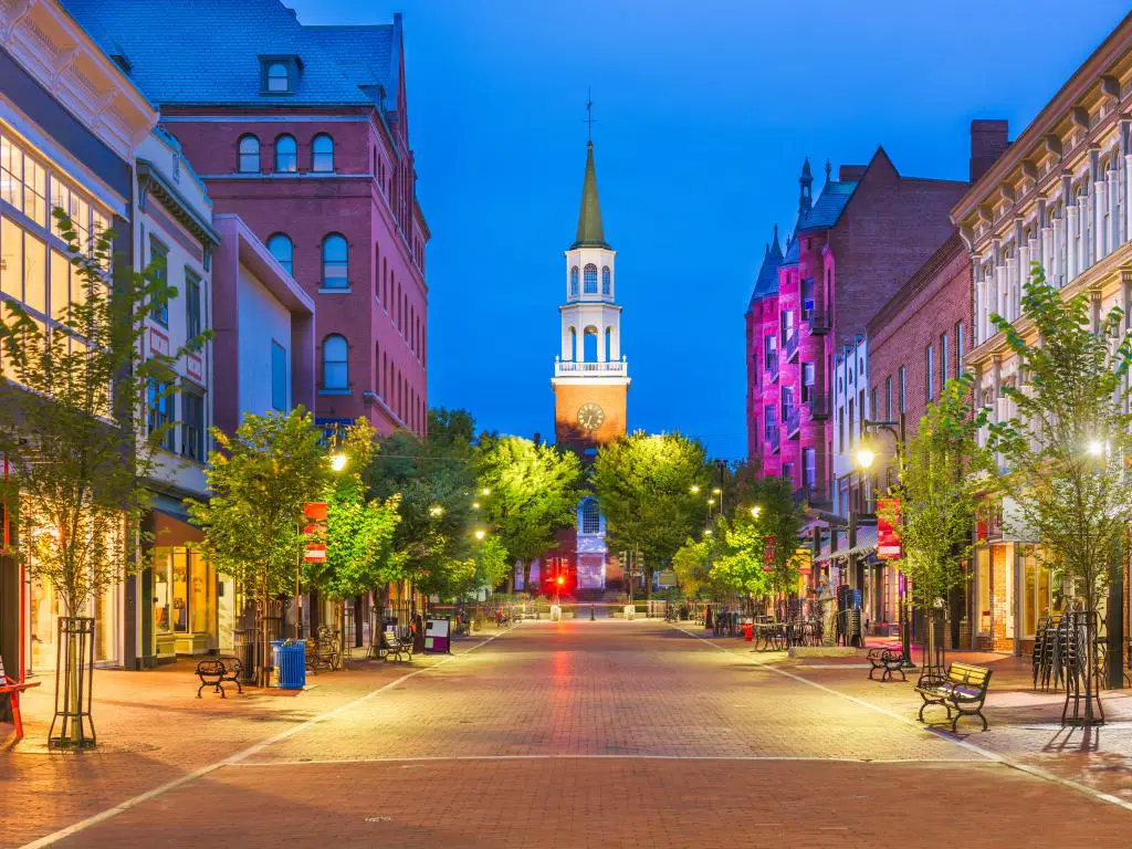 Burlington, Vermont, EE.UU. en Church Street Marketplace al atardecer con árboles que bordean la calle y la torre del reloj en la distancia.