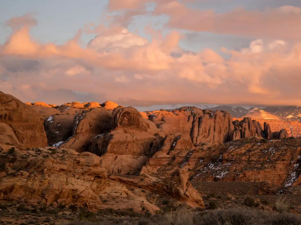 Montañas La Sal, Moab, Utah, EE.UU. con una colorida puesta de sol sobre capas de aletas rocosas del desierto en Moab mirando hacia las montañas La Sal.