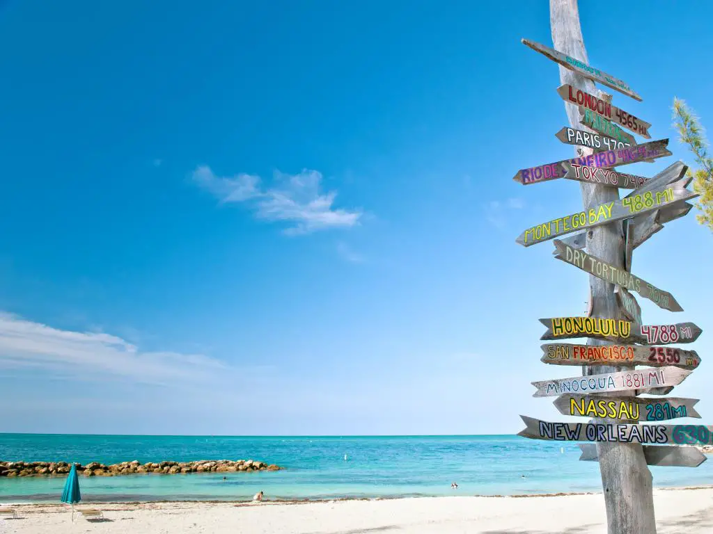 Key West, Florida, EE.UU. con el cartel de kilometraje en la playa en un día soleado.