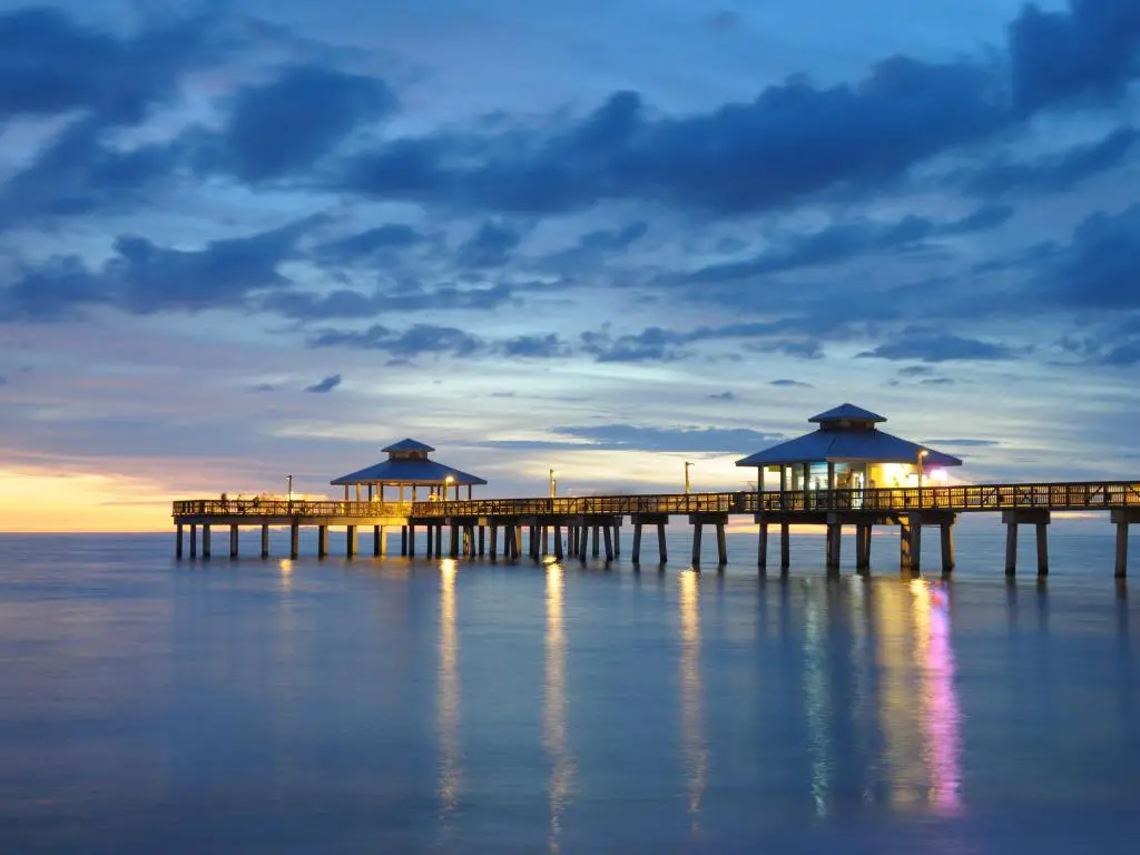 Muelle de Fort Myers al atardecer, Florida, EE.UU. con las luces en el muelle reflejadas en el mar de abajo.