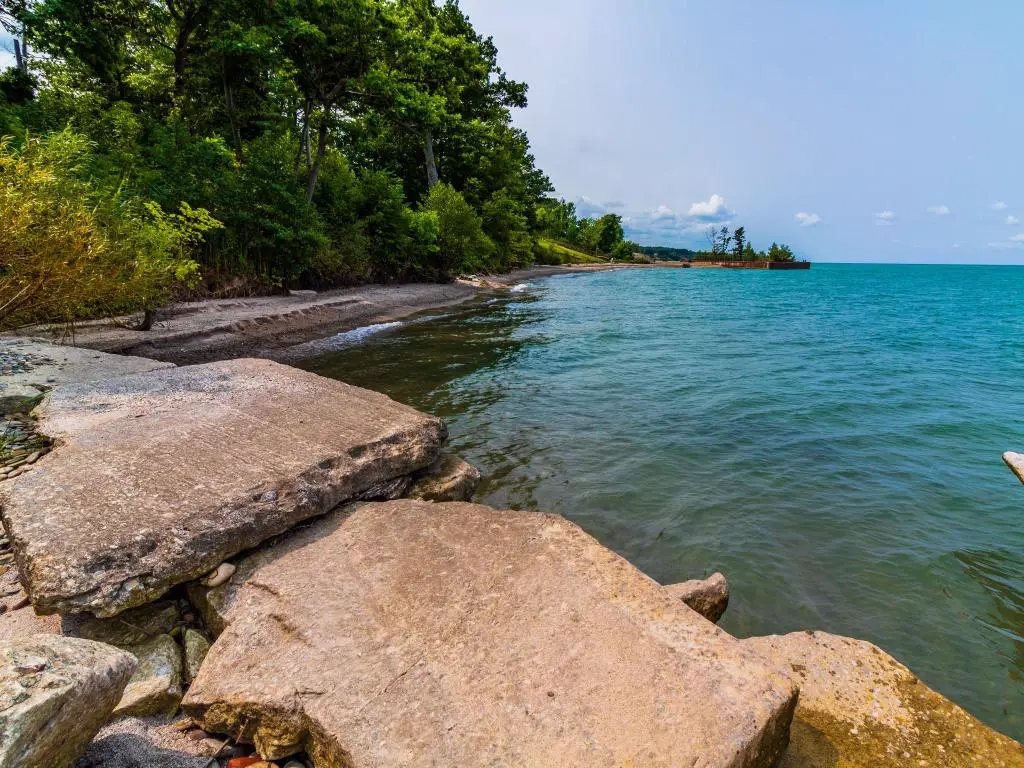 Lago Erie, Ohio, EE. UU. Con la costa en primer plano y tomada en Rubes Landing en un día soleado, los árboles conducen a la distancia. 