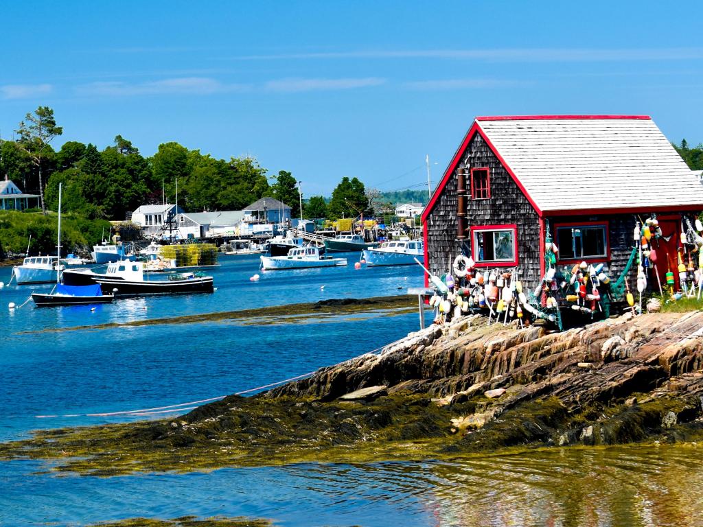 Boat House en Bailey's Island en Harpswell, Maine, tomada en un día soleado con barcos en la distancia. 