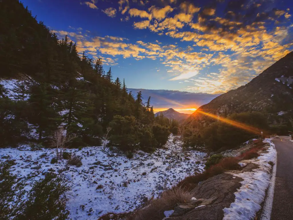 Atardecer en el Monte Baldy cubierto de nieve en invierno con un camino que serpentea a través de los picos altos y nubes coloridas en el cielo