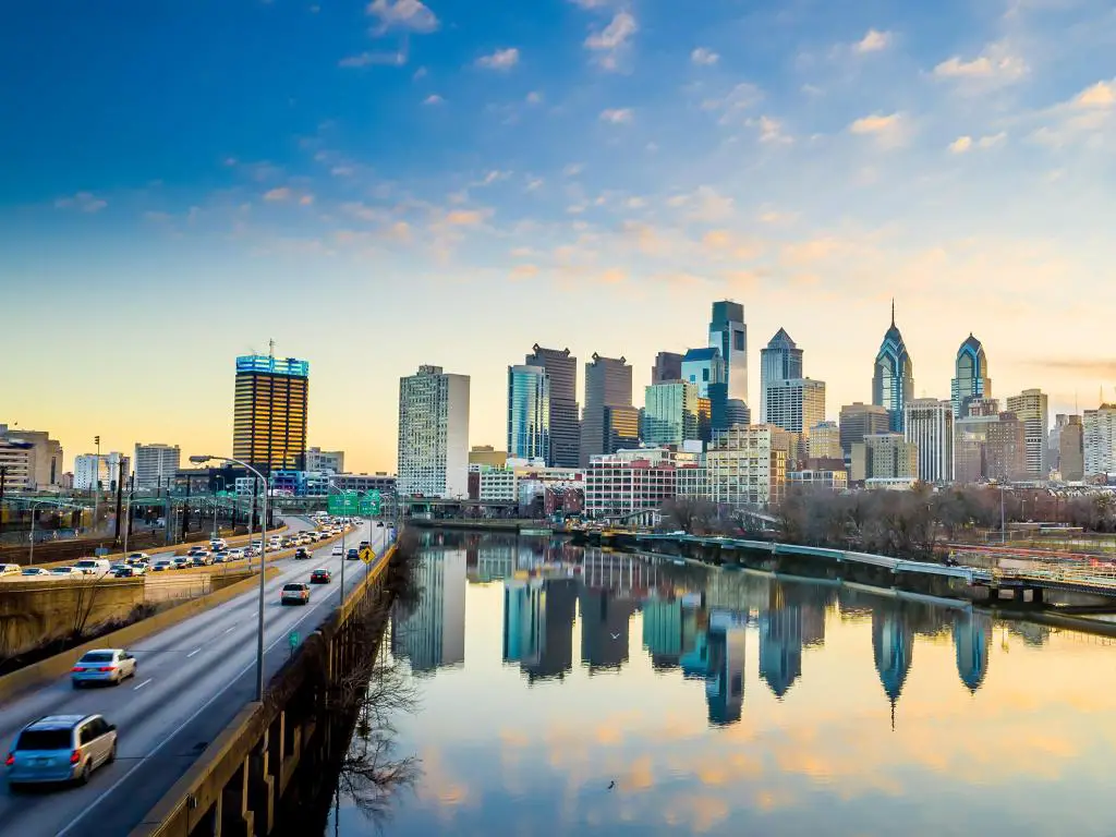 Filadelfia, Pensilvania, EE.UU. tomada con el horizonte del centro de la ciudad al atardecer, una carretera y un río que corren hacia él.