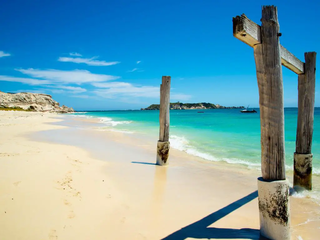 Playa de arena blanca con estructura de madera en primer plano, mar turquesa y cielo azul