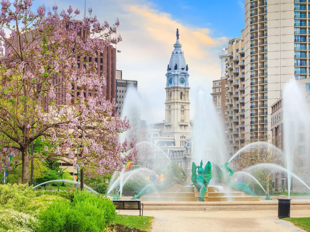 Filadelfia, Pensilvania, Estados Unidos, tomada en la fuente conmemorativa de Swann con el ayuntamiento al fondo, una flor rosa y un cielo azul.