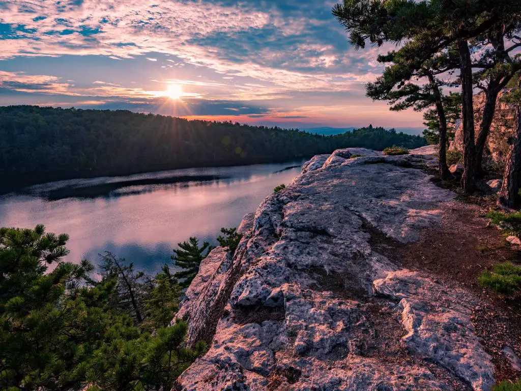 Minnewaska State Park, Nueva York, EE.UU. con el lago Minnewaska y grandes rocas y árboles en primer plano, tomadas al atardecer.