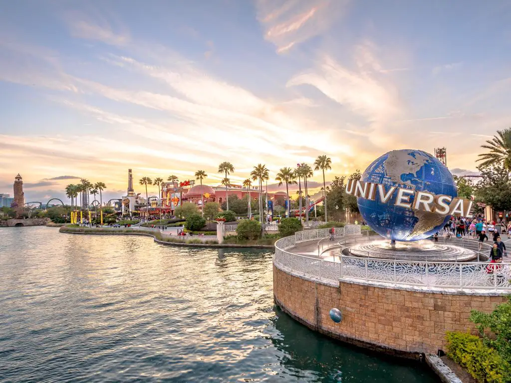 Orlando, Florida, EE. UU. Con el globo Universal Studios ubicado en la entrada del parque temático en primer plano, rodeado de agua y el parque a lo lejos tomado al atardecer.