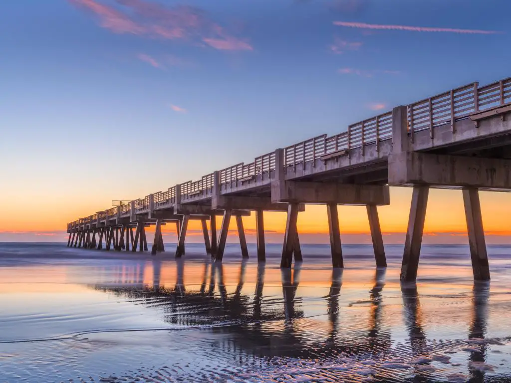 Jacksonville, Florida, EE.UU. con vistas a la playa y al muelle de Jacksonville tomadas al amanecer con un mar en calma y un cielo impresionante.
