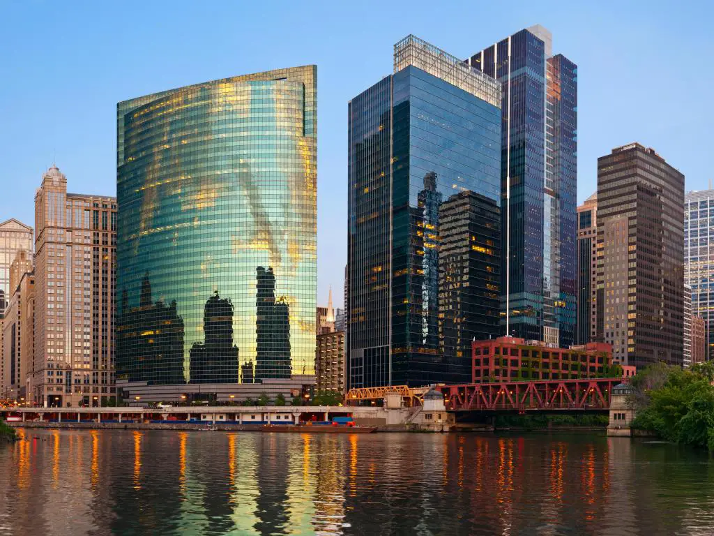Chicago Downtown, Illinois, EE.UU. tomada en verano al atardecer con el distrito del centro en el fondo reflejándose en el agua en primer plano y tomada contra un cielo azul claro.