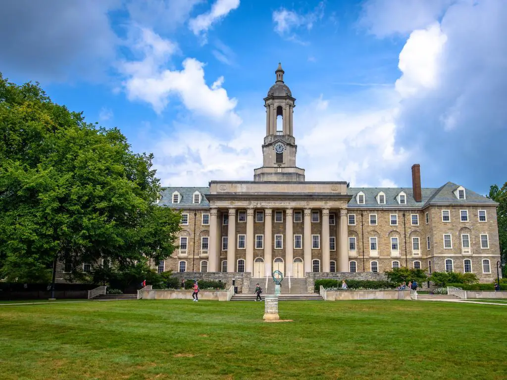 State College, Pensilvania, EE.UU. con el antiguo edificio principal en el campus de la Universidad Estatal de Penn, tomada en un día soleado con césped en primer plano.