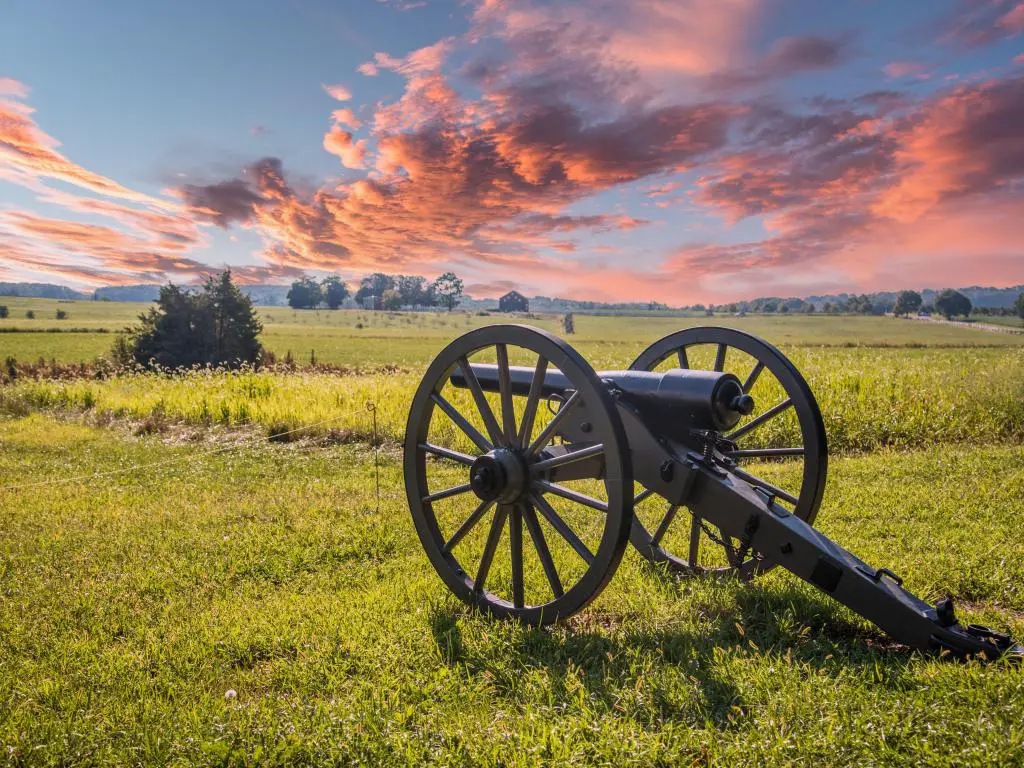 Gettysburg, EE. UU. Con un canon apuntando a un campo de batalla rodeado de hierba y tomado al atardecer con un hermoso cielo arriba.