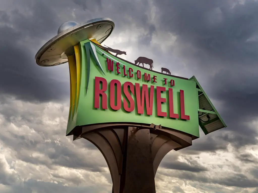 Bienvenido al cartel de Roswell (Nuevo México) con animales que se transmiten a una nave espacial de platillo volador.