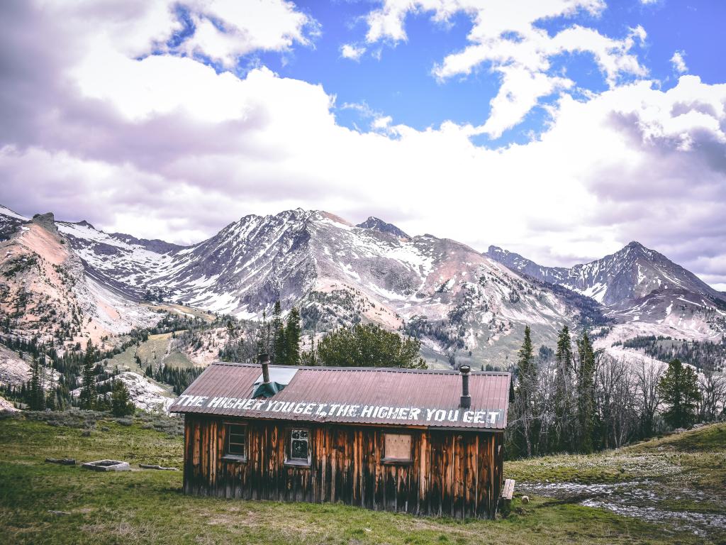 Ketchum, Idaho, EE. UU. con una cabaña pionera en primer plano y las montañas Pioneer al fondo cubiertas de nieve.