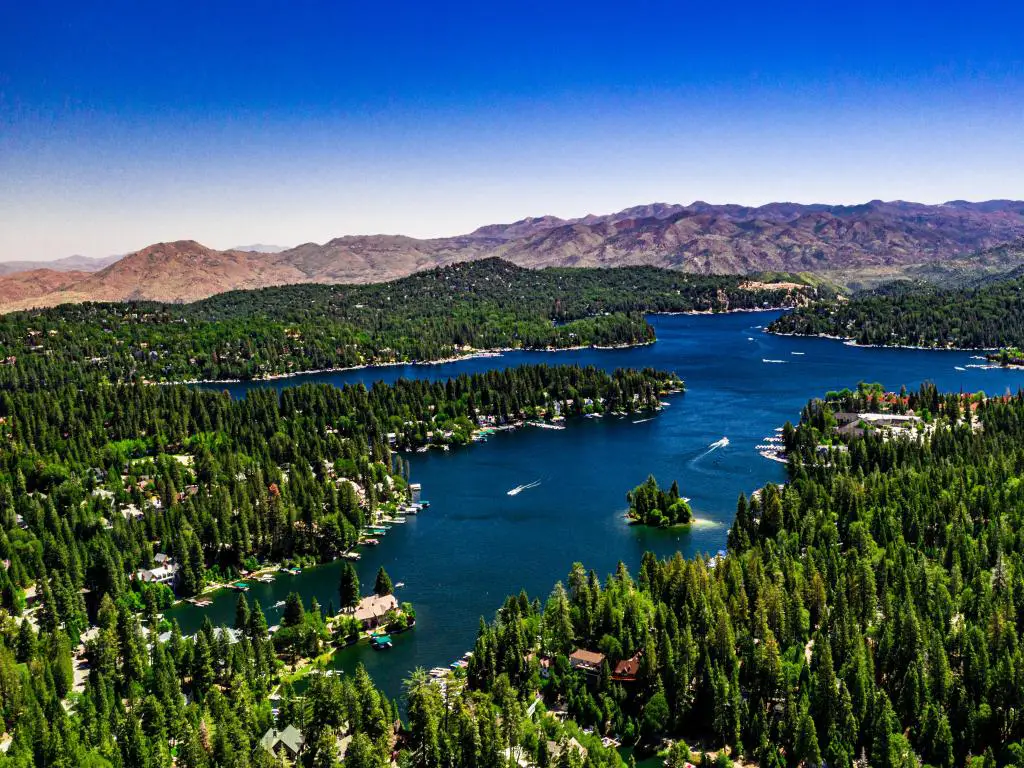 Lake Arrowhead, montañas de San Bernardino, California, EE.UU. tomado como un panorama aéreo de drones del lago en un día claro de verano con agua azul y cielo, montañas moradas y árboles verdes.