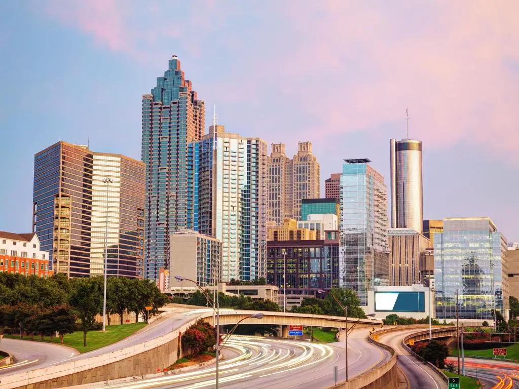Autopista que pasa por el centro de Atlanta con edificios altos iluminados con luz rosa claro