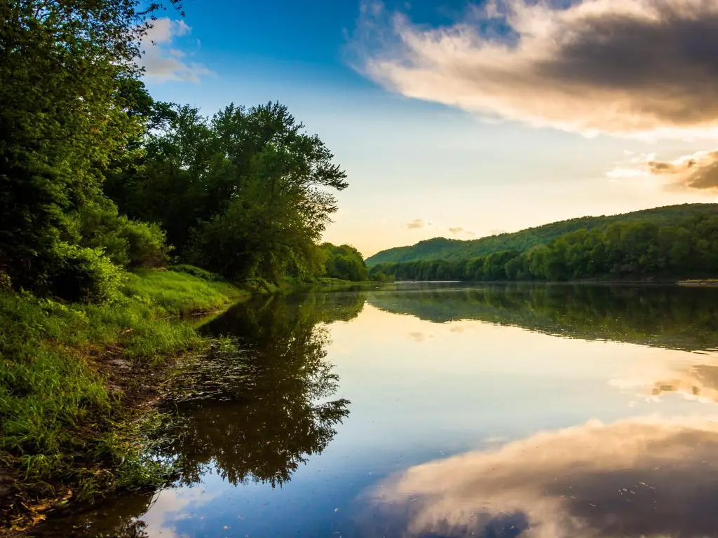 Río Delaware, Nueva Jersey, EE. UU. Tomado con reflejos nocturnos en el río en primer plano y rodeado de exuberantes tierras verdes y árboles a ambos lados. 