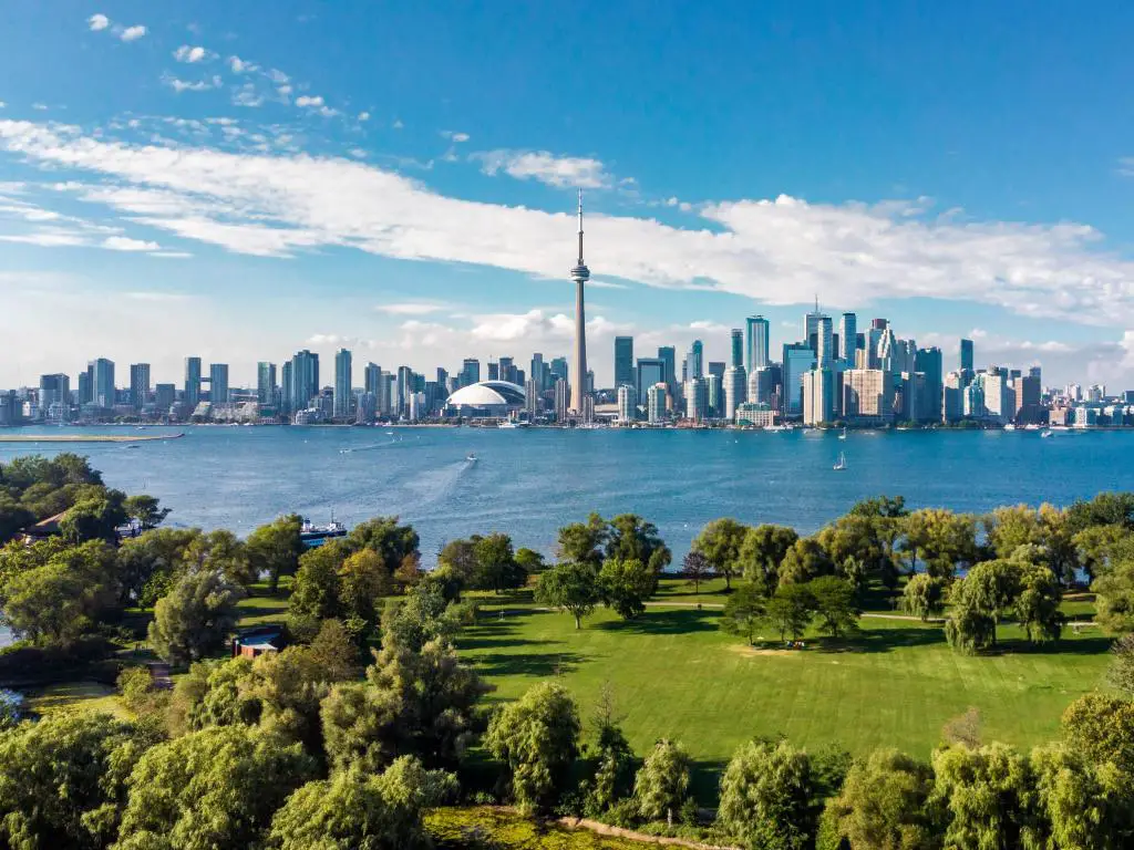 Lago Ontario, Toronto, Ontario, Canadá con el horizonte de la ciudad al fondo y el lago Ontario y un parque verde en primer plano en un día claro y soleado. 