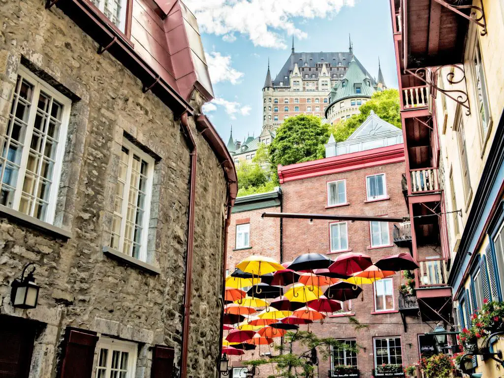 Ciudad de Quebec, Canadá, una calle típica con sombrillas colgando de los edificios y el gran edificio en el fondo tomado en un día soleado. 