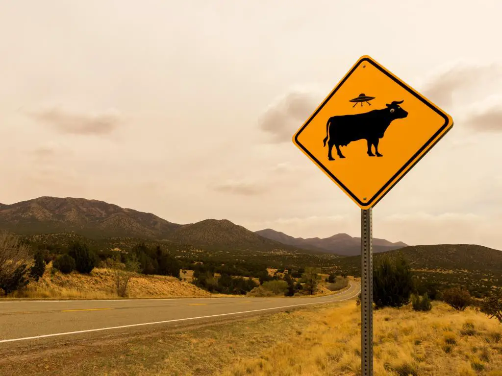 Señal de carretera de abducción alienígena de vaca a lo largo del sendero Turquoise Trail, Route 66 Scenic Byway, en primavera entre Santa Fe y Albuquerque, Nuevo México.