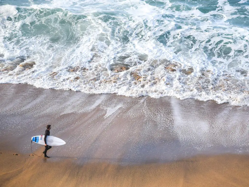 Hombre con una tabla de surf en Torquay, Australia 