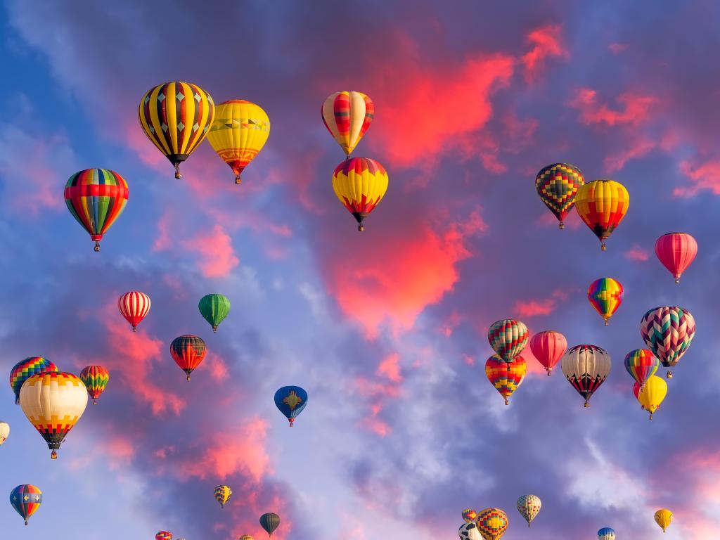 Coloridos globos aerostáticos en vuelo iluminados por la luz de la mañana en los cielos de Albuquerque.