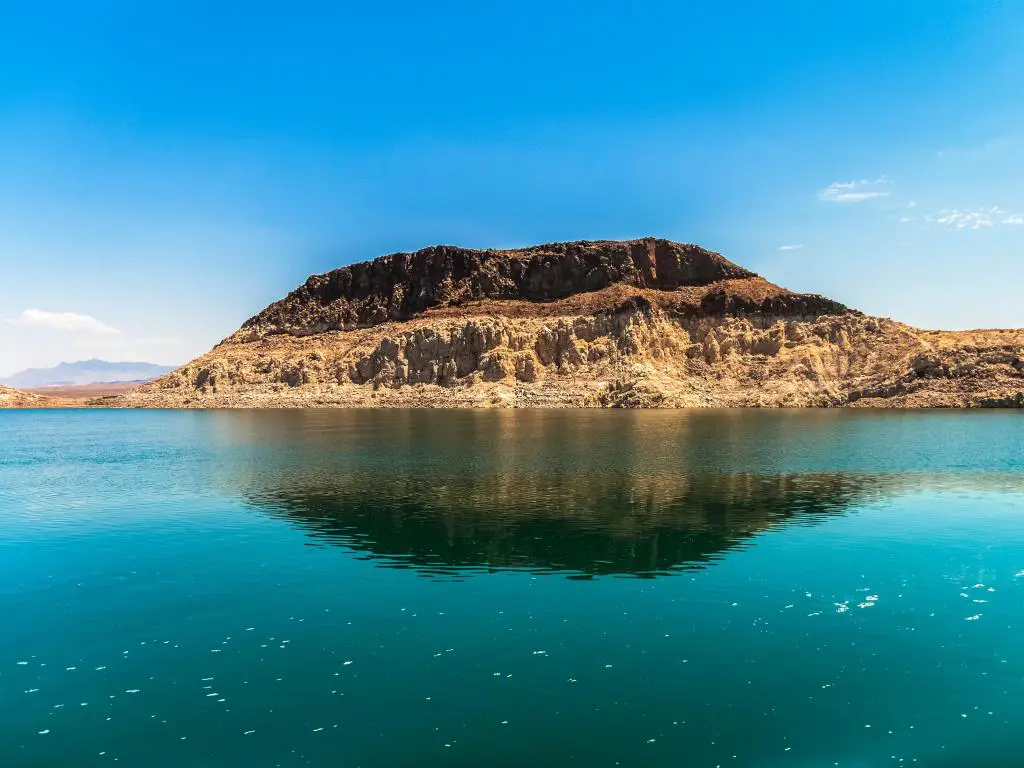 Lago Mead, Área Nacional de Recreación, Nevada, EE.UU. con una gran formación de roca sedimentaria rodeada de agua clara en un día soleado.