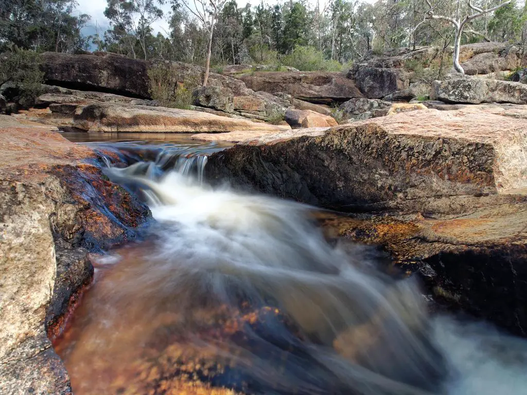 Cascada de río pequeña cascada a través de riberas rocosas planas en Woolshed Falls, Beechworth, Victoria, Australia