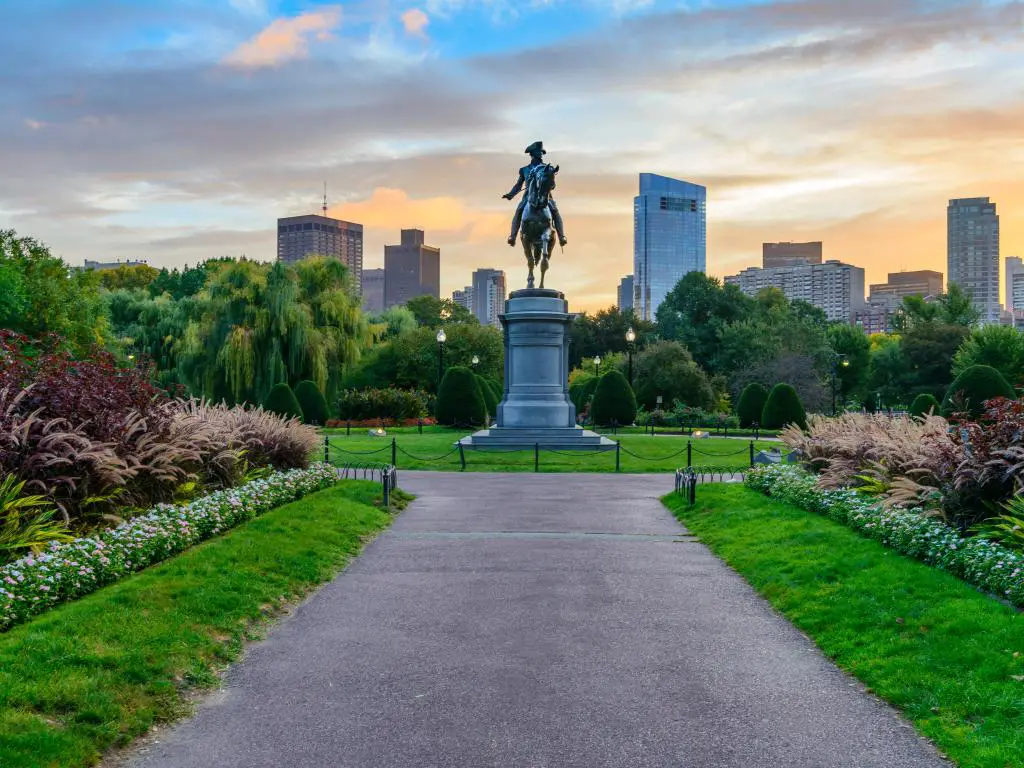 Boston Public Garden, Boston, EE.UU. con la estatua de Washington en Boston Public Garden y el horizonte en la distancia tomada al atardecer.