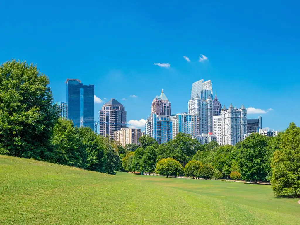 Atlanta, EE.UU. con el horizonte de la ciudad en el fondo y el impresionante parque verde en primer plano con árboles que separan los dos en un día soleado. 