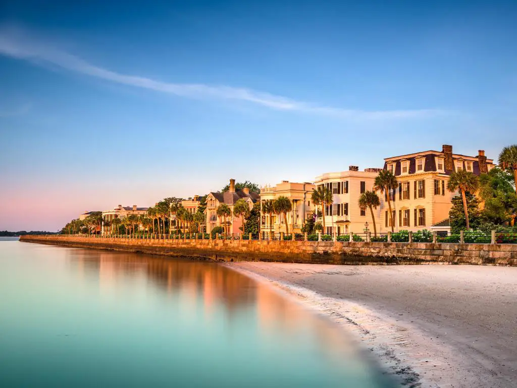 Edificios blancos históricos justo en el paseo marítimo con palmeras en fila y una pequeña sección de playa