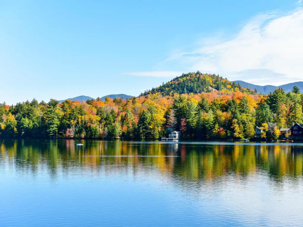 Lake Placid, Nueva York, EE.UU. con el follaje de otoño de Adirondacks Peak en el fondo y las tranquilas aguas del lago en primer plano tomadas en un día claro y soleado. 