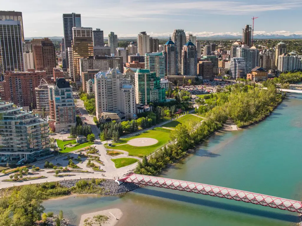 Calgary, Alberta, Canadá con Peace Bridge sobre Bow River y el horizonte del centro de la ciudad en la distancia en un día soleado.