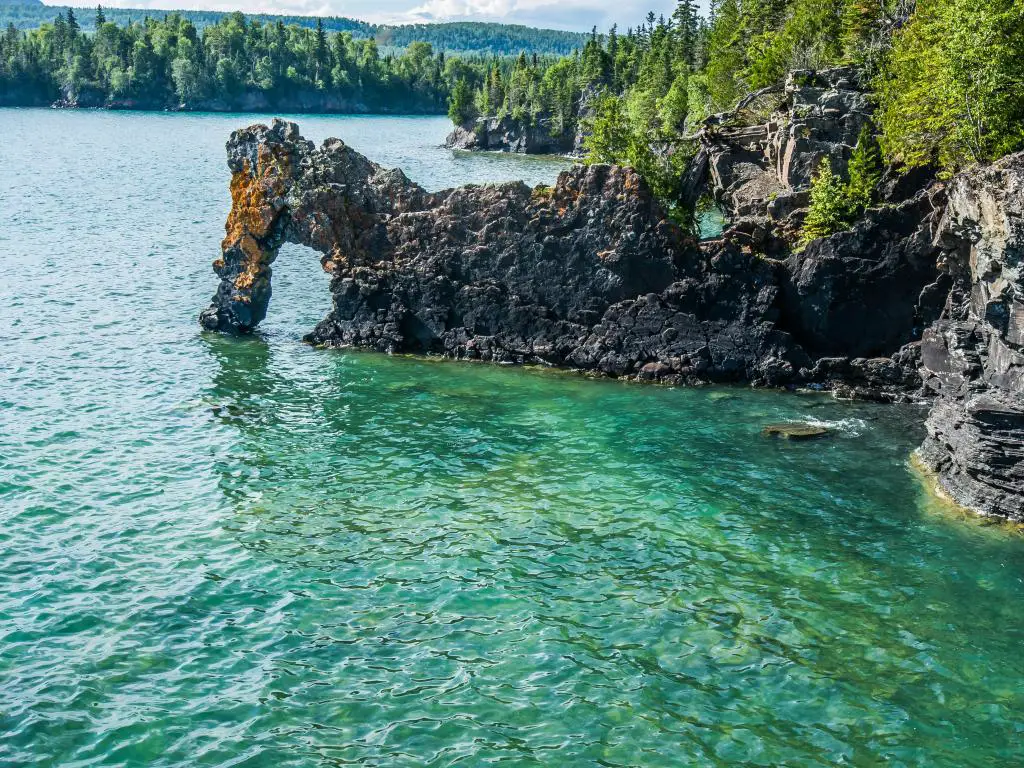 Thunder Bay, Ontario, con una formación rocosa llamada Sea Lion, en primer plano y rodeada por el lago Superior, con árboles a lo lejos en un día soleado.