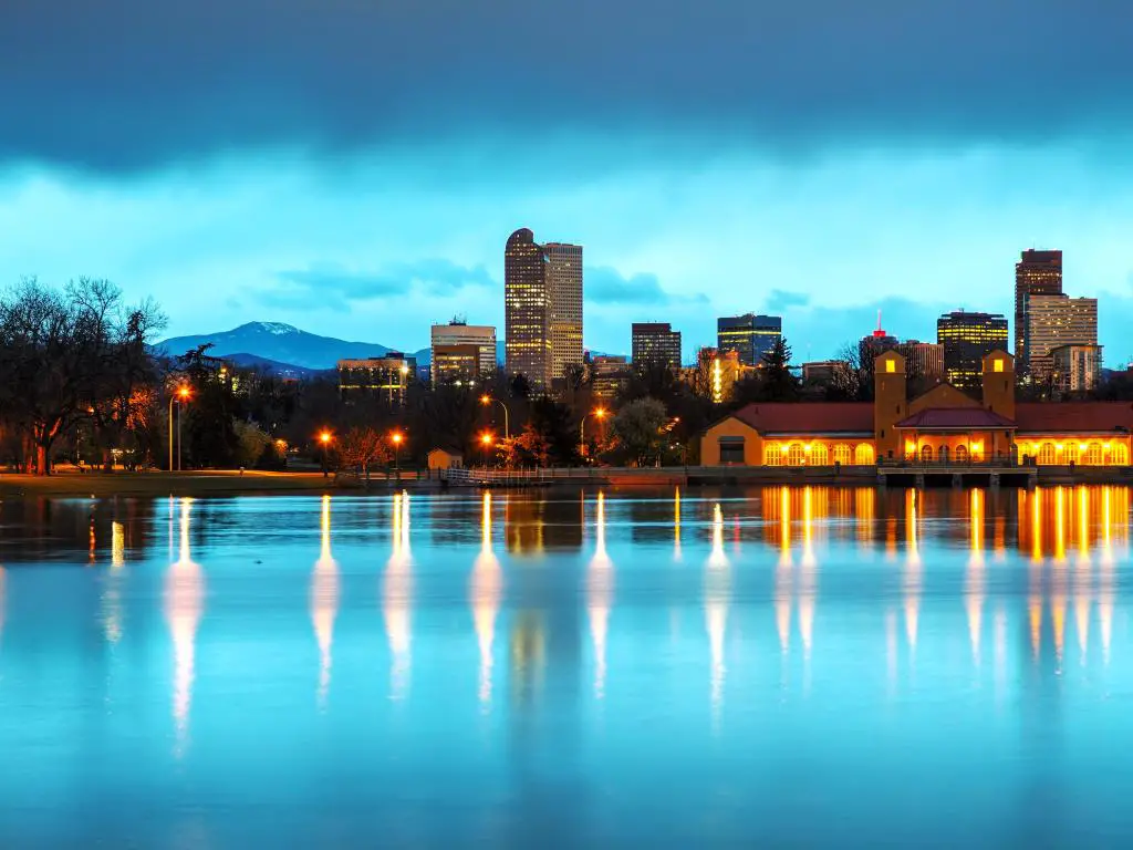 Los edificios de la ciudad se reflejan en el agua del lago en la luz azul de la mañana temprano con las montañas en el fondo