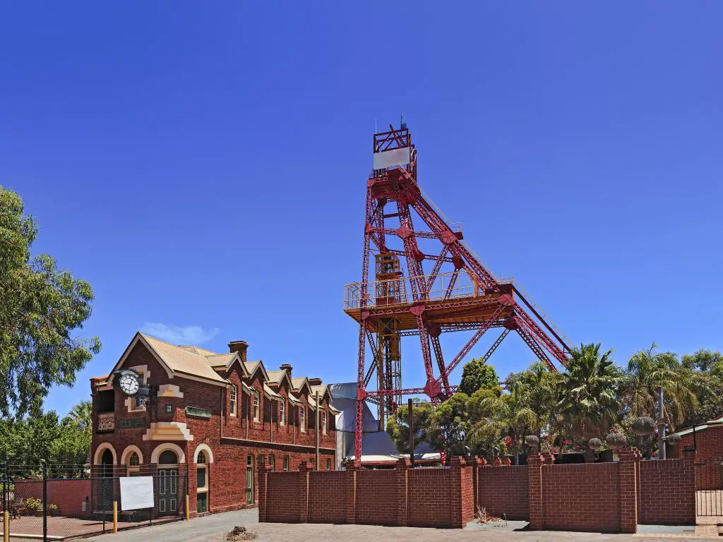 Edificio histórico de ladrillo rojo y torre de maquinaria de minería industrial con cielo azul y eucalipto