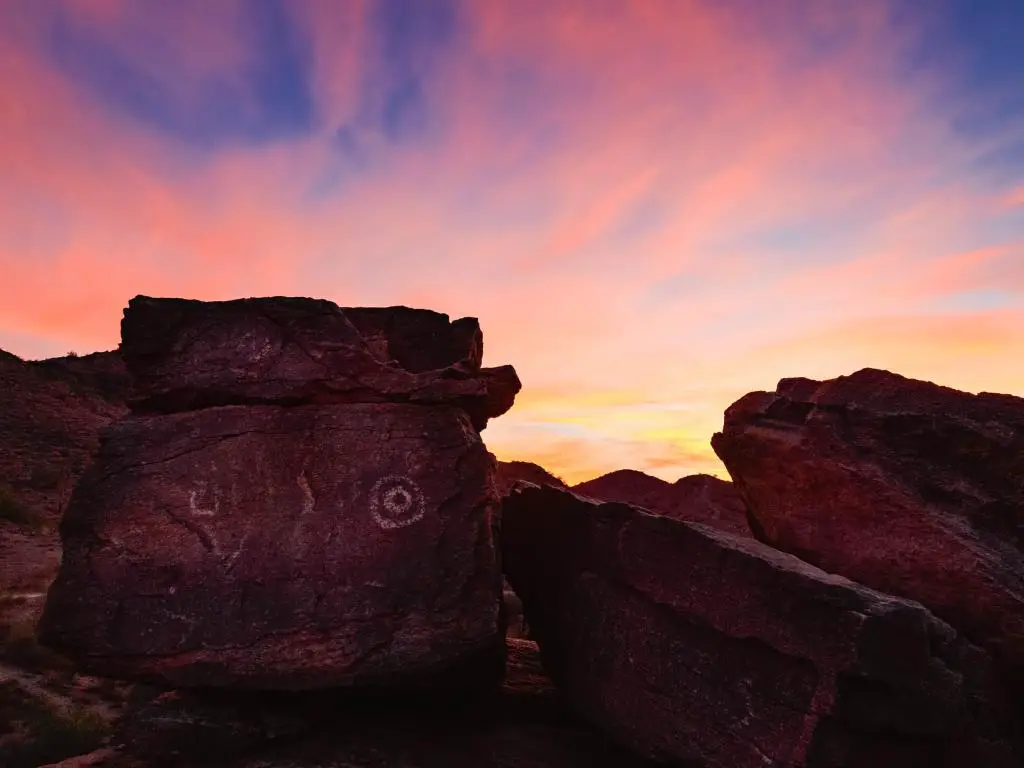 Monumento Nacional de Petroglifos, Albuquerque, EE.UU. con arte rupestre/petroglifos de Hohokam en primer plano al atardecer contra un cielo soleado.