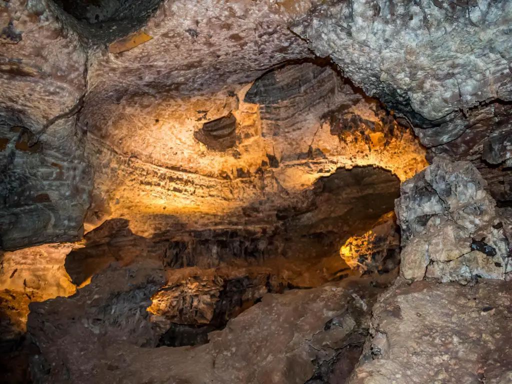 Parque Nacional Wind Cave, Dakota del Sur, dentro de la cueva con formación geológica de rocas iluminadas con un resplandor amarillo. 