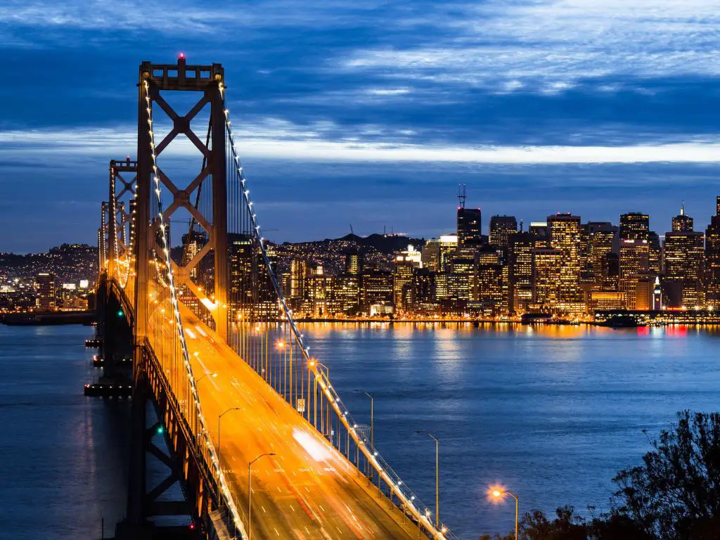 Puente Golden Gate, San Francisco de noche con el puente iluminado en amarillo y la ciudad al fondo.